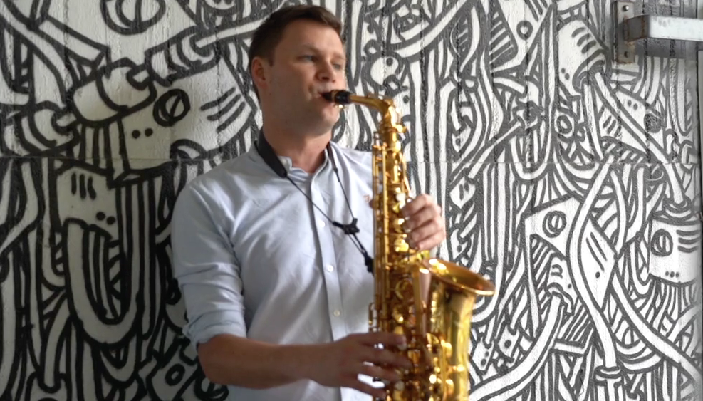 mann mit sxophon vor grafittywand