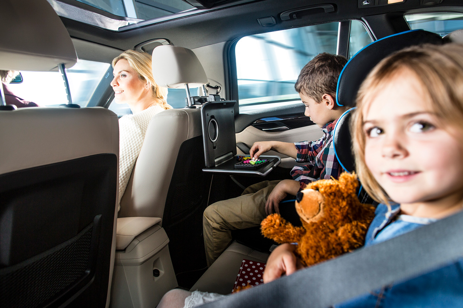 Blick in ein BMW Auto von hinten durch die Rücksitzscheibe, ein kleines Mädchen ist zu sehen und ein Junge, weiter vorne sieht man die Beifahrerin und den Innenraum des Fahrzeugs