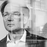 Portrait von Matthias Tschöp durch Glasscheiben, LMU und Helmholtz Institut