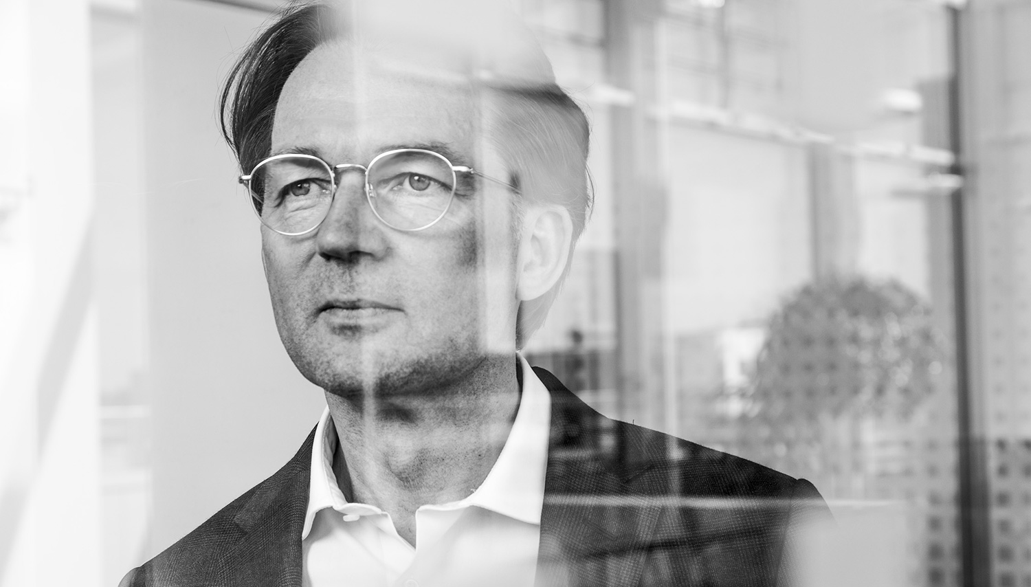 Portrait von Matthias Tschöp durch Glasscheiben, LMU und Helmholtz Institut