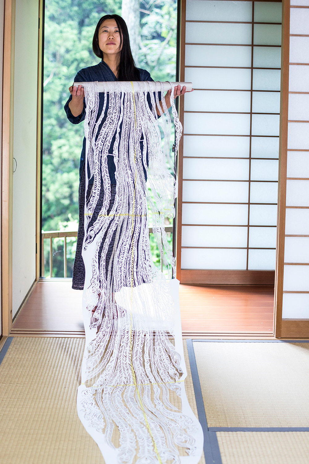 Scherenschnitt Künstlerin in einem japaischem Raum mit einer langen Papierrolle