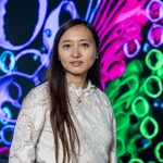 Portrait einer Mikrobiologin mit farbigen zellstrukturen im Hintergrund