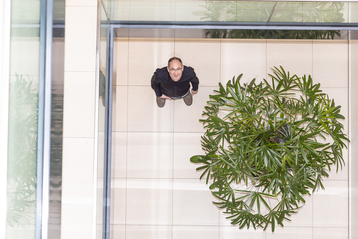 Portrait von oben auf einen Menschen neben einer exotischen Pflanze in einem Gebäude
