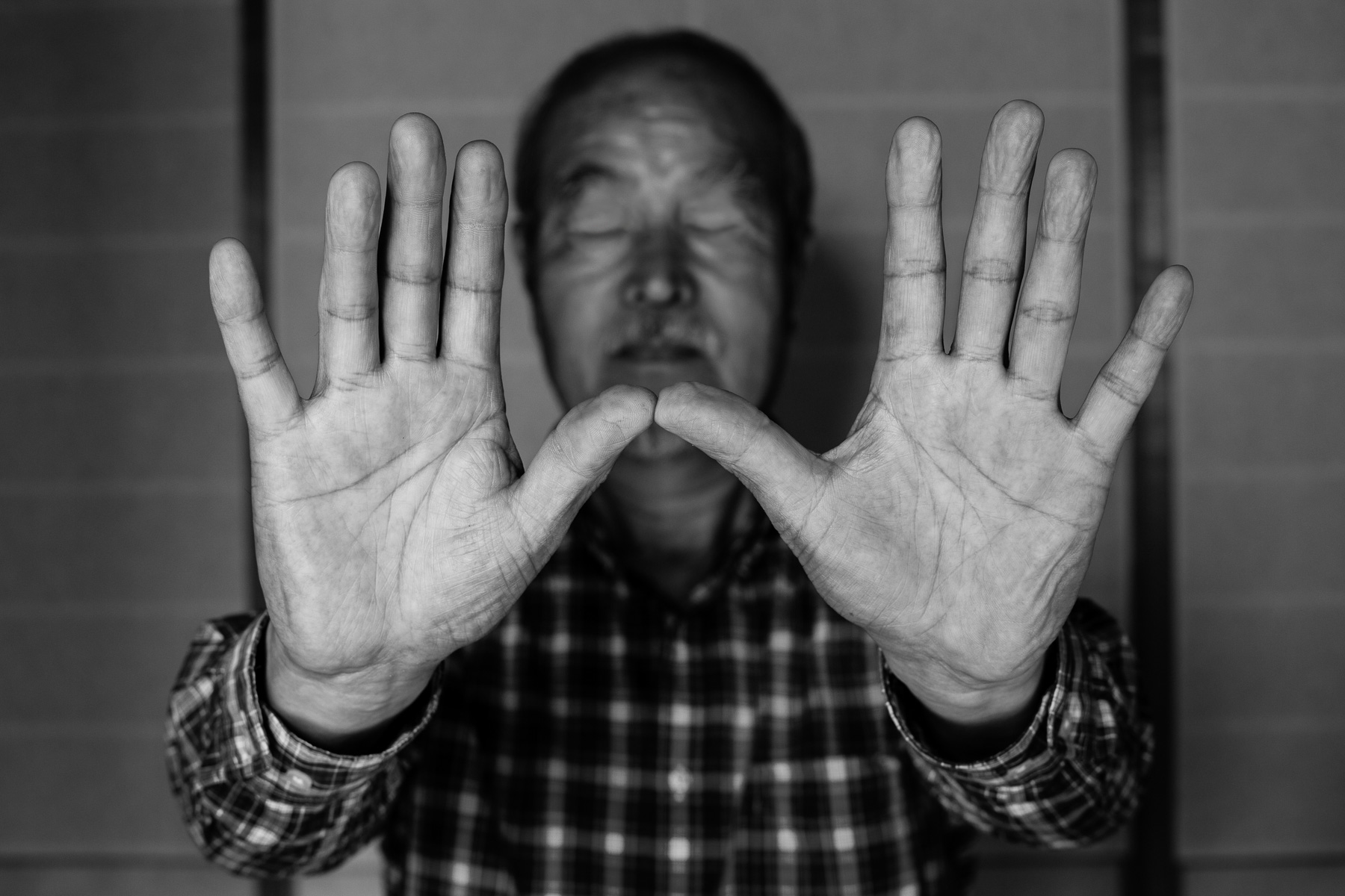 Portrait eines berühmten japanischen Töpfers, seine beiden Hände sind nach vorne ausgetreckt, seine Augen geschlossen