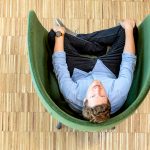 Ein Mann in einem Sessel fotografiert von oben, er schaut hoch direkt in die Kamera