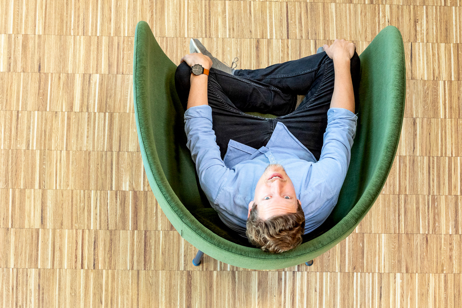 Ein Mann in einem Sessel fotografiert von oben, er schaut hoch direkt in die Kamera