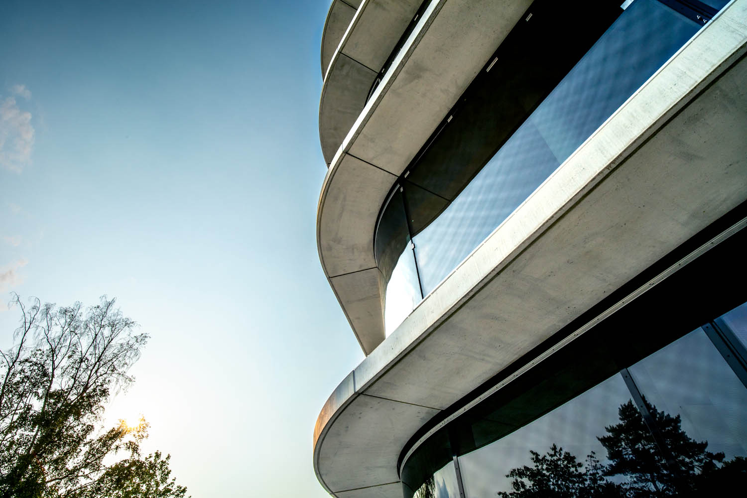 Ausschnitt einer Außenfassade mit großen runden Fenstern, die Etagen trennen sich durch Betonebenen die heraus stehen.