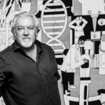 Schwarz Weiss Portrait eines Wissenschaftlers vor einer Comic Wand mit Bildern aus Forschung und Labortechnik und Biologie