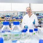 Portrait eines Wissenschaftlers in einem medizinischen Labor mit vielen Flaschen und Reagenzgläsern