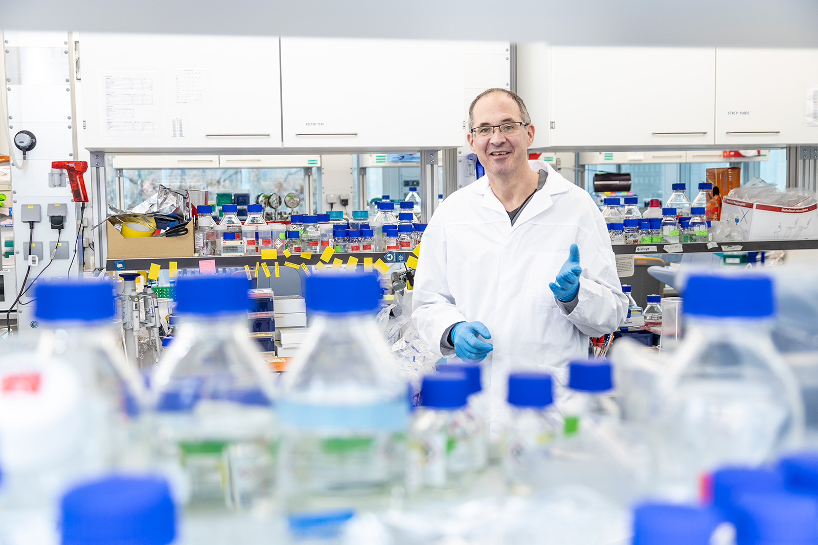 Portrait eines Wissenschaftlers in einem medizinischen Labor mit vielen Flaschen und Reagenzgläsern