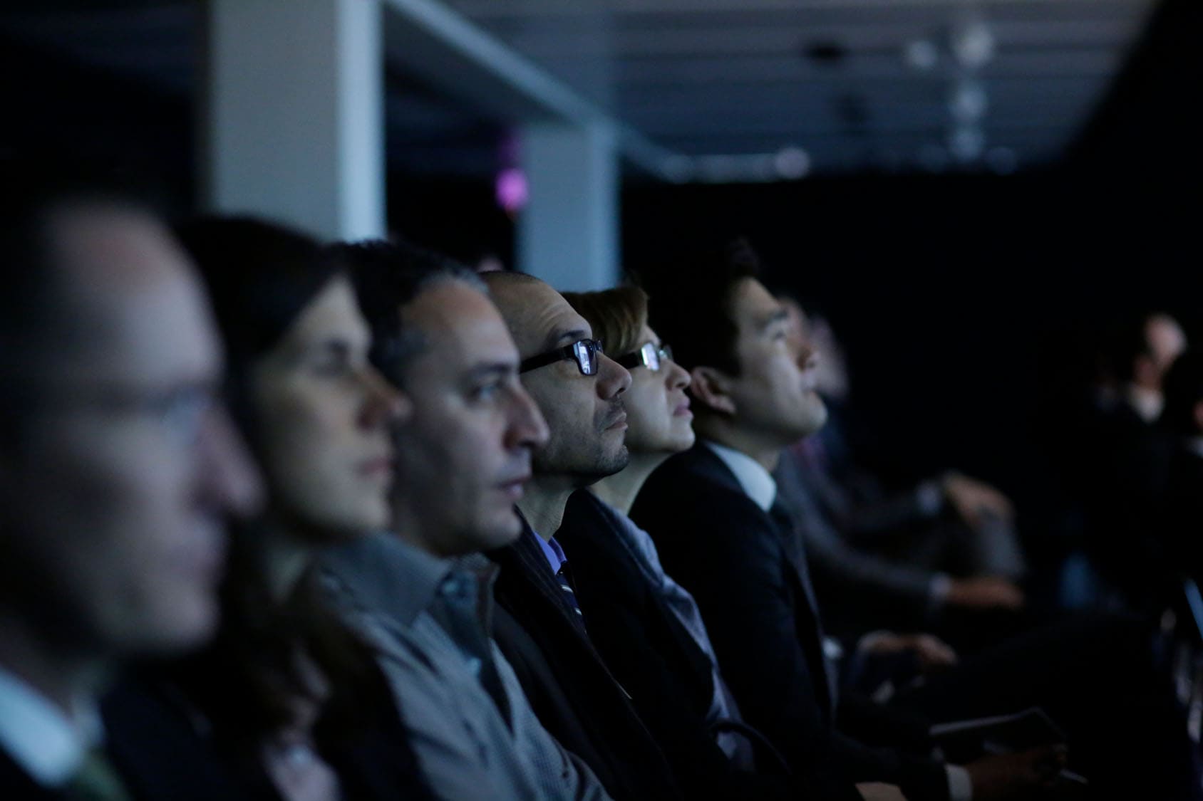 Menschen in einer Reihe sitzend schauen auf eine Bühne bei einem Vortrag