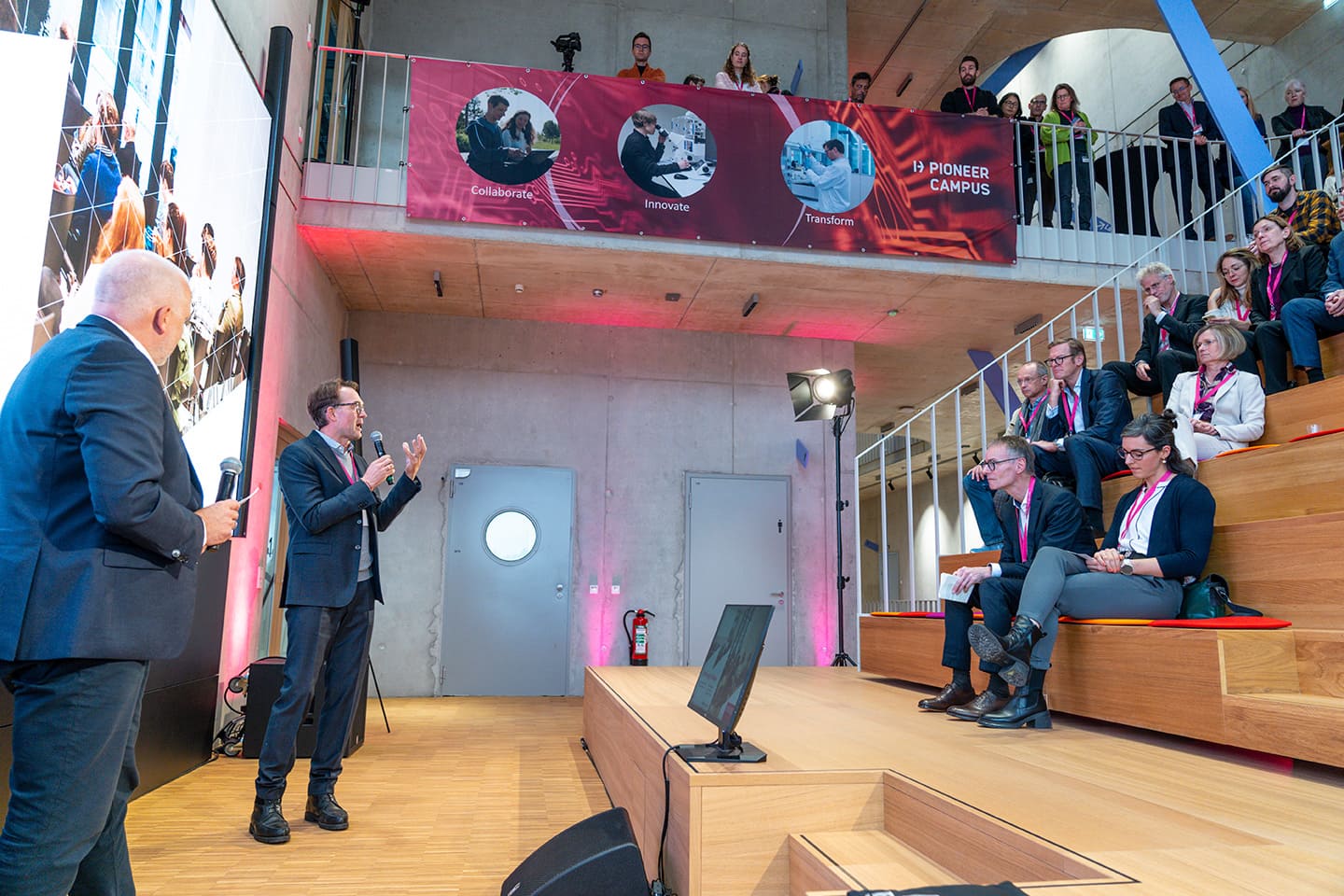 Redner vor einer Gruppe mit Menschen auf einer Bühne