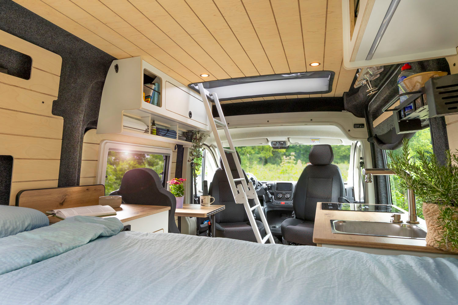 Ausgebauter Camping Bus von innen fotografiert, mit Treppe, Bett und gedrehten Vordersitzen