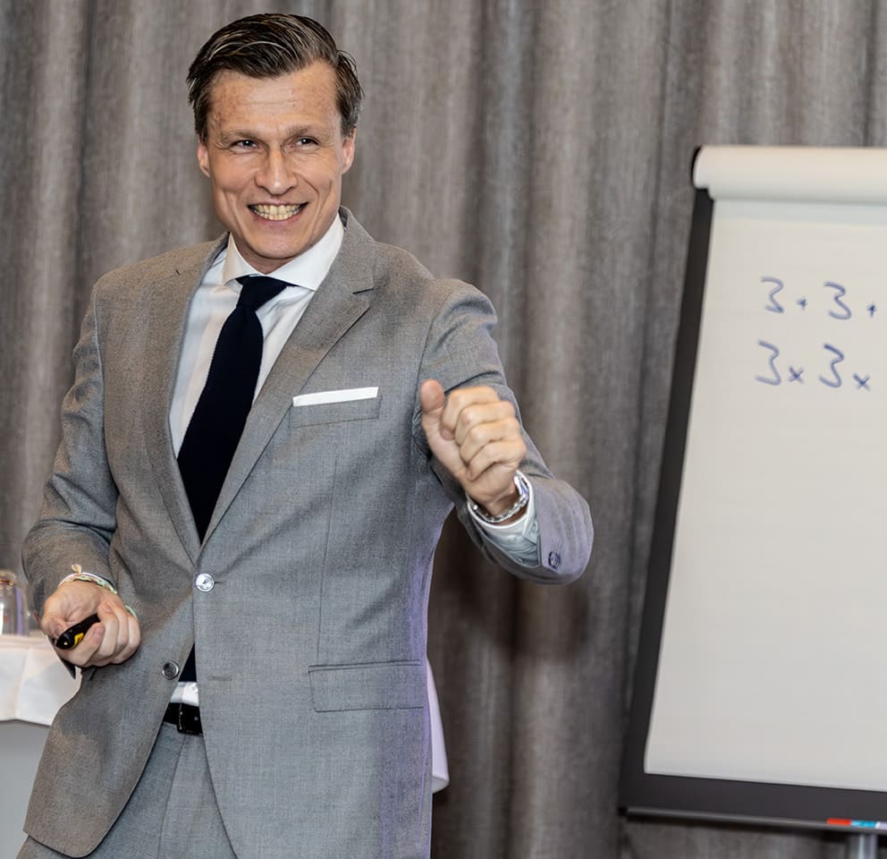 redner vor einem flipchart lächelnd zum publikum