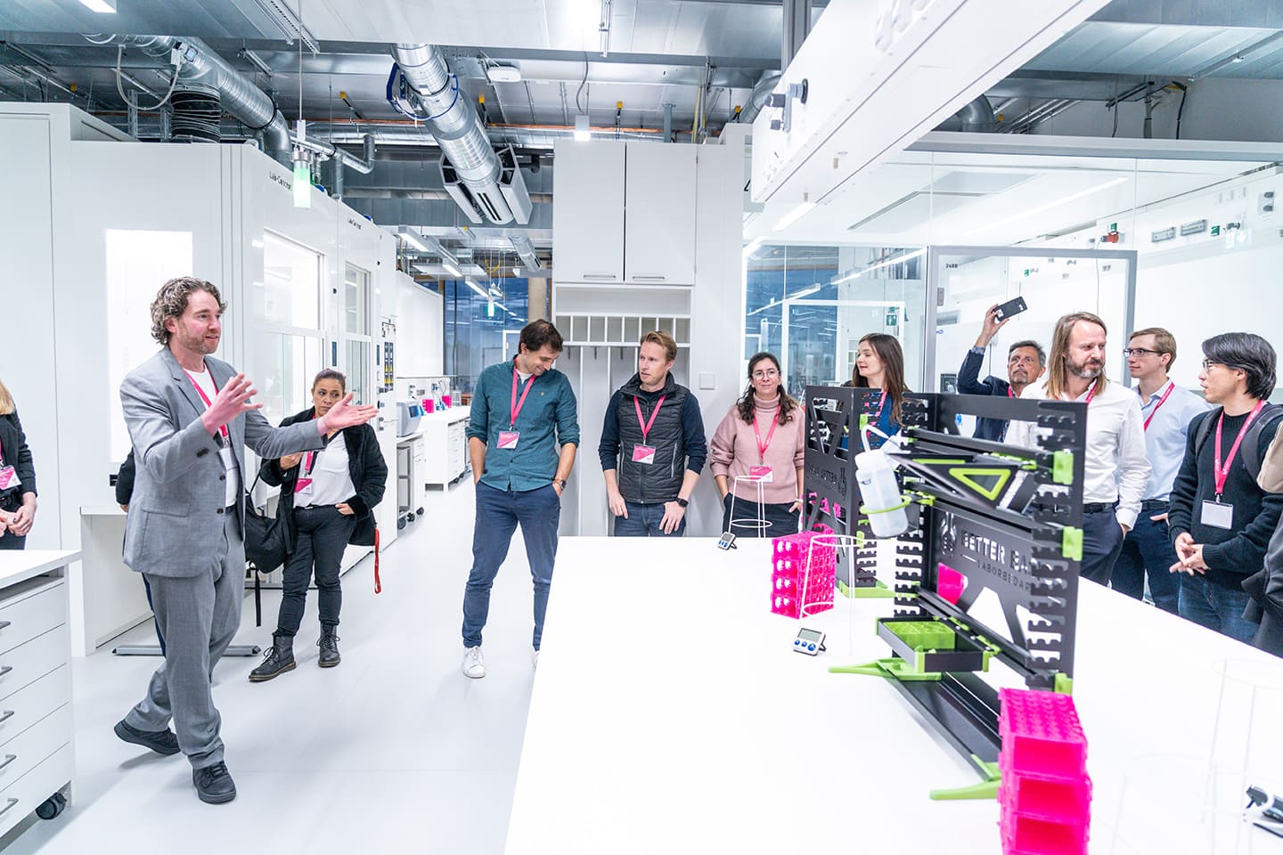 Redner vor einer Gruppe Menschen in einem wissenschaftlichen Labor