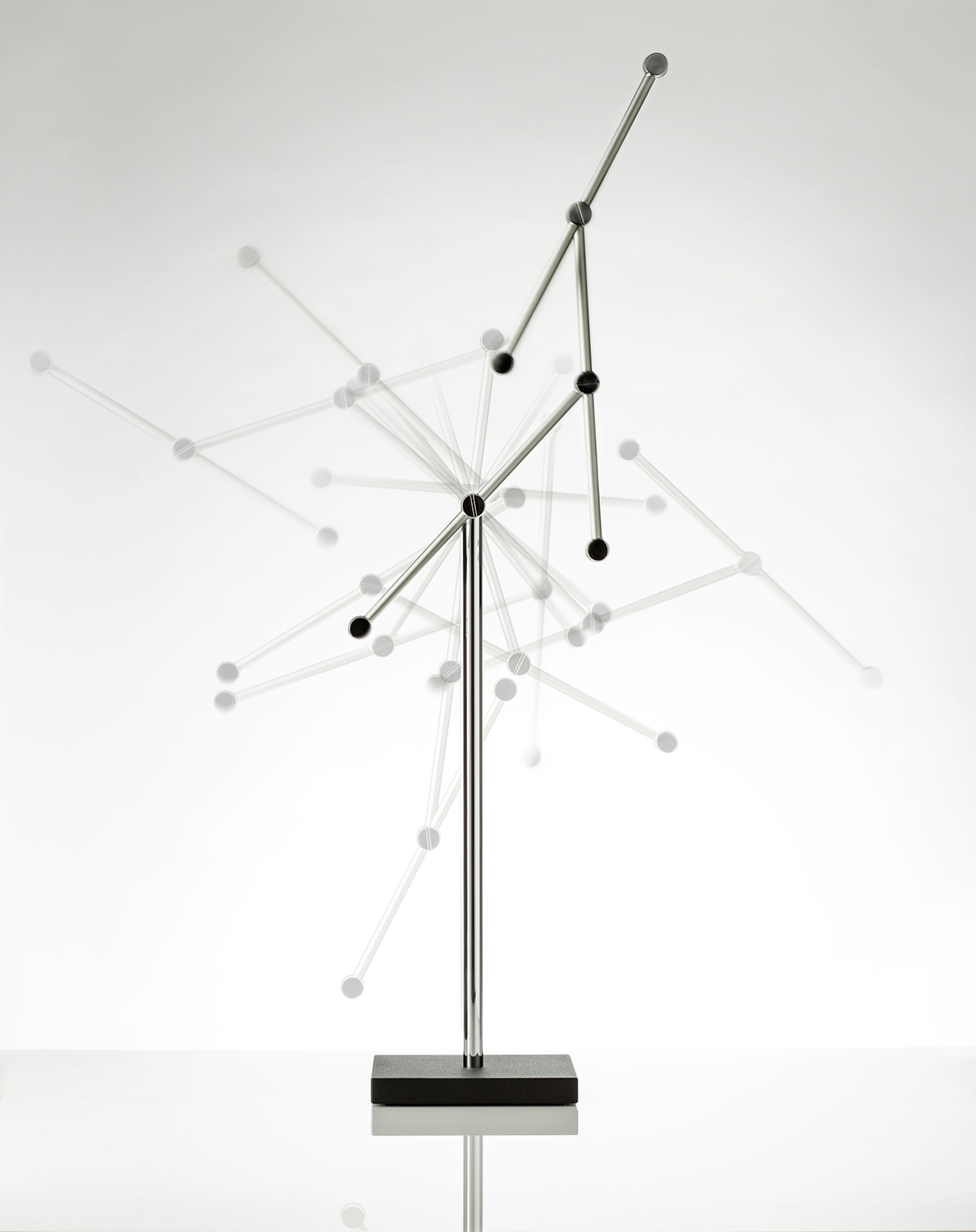 Bild eines Tripendulum Modells in Bewegung mit Mehrfachbelichtung vor weißem Hintergrund