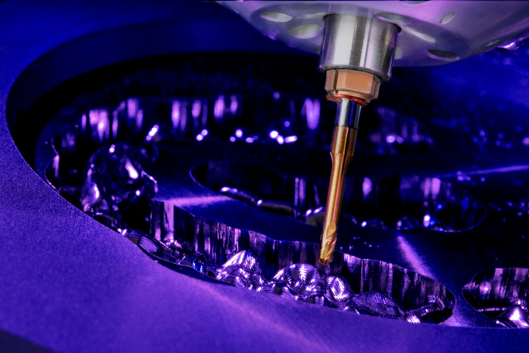 Eine Fräsmaschine arbeitet sich durch eine Zirkonronde im close up bunt fotografiert mit lila licht und gelben bohrer