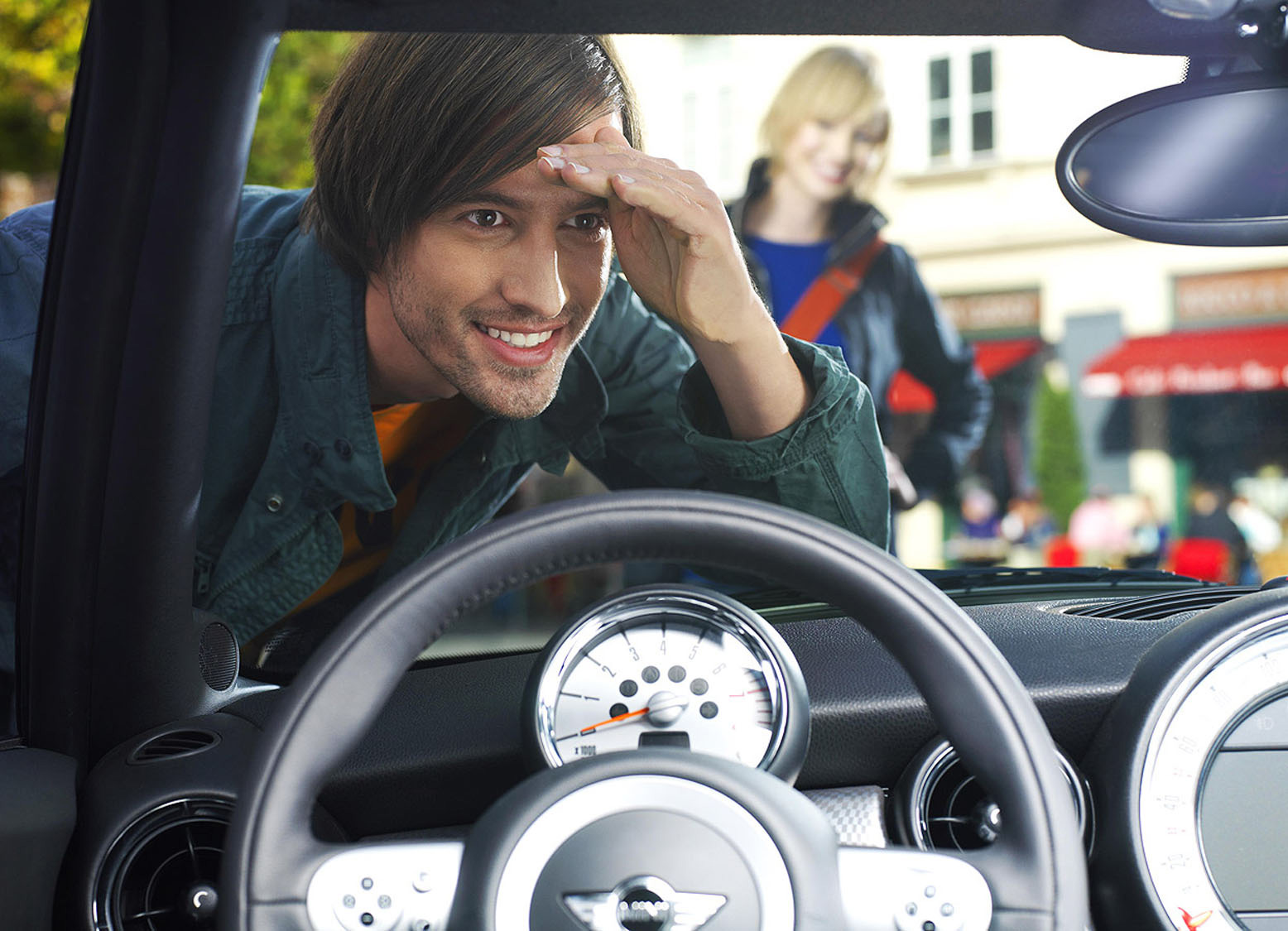 Ein Mann schaut von außen neugierig durch die Frontscheibe eines Autos